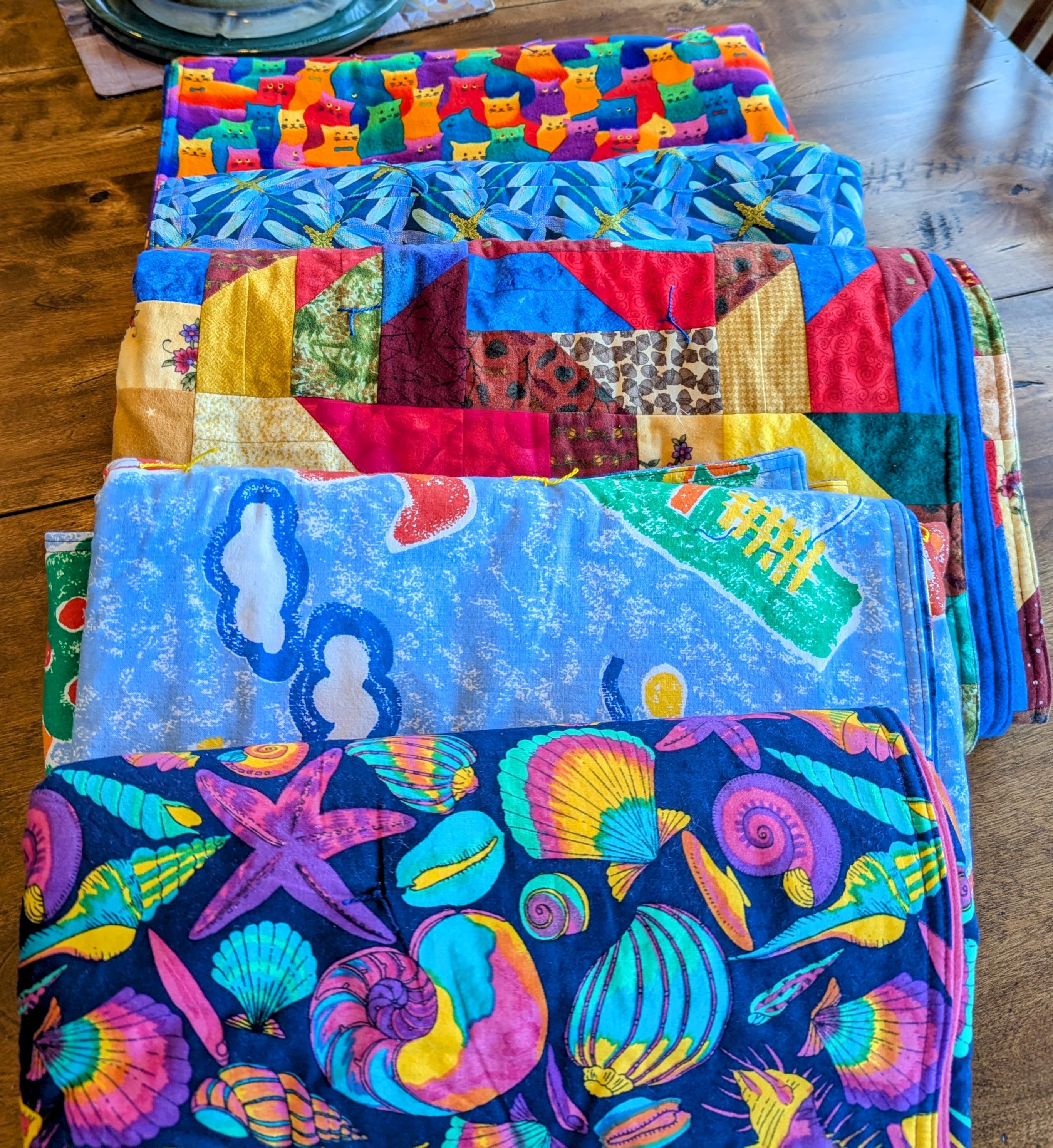 Assortment of colorful folded quilts ready for donation to children and teens at CARES Northwest.